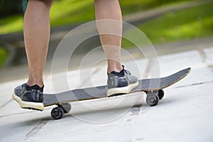 Young skateboarder legs riding skateboard at skatepark