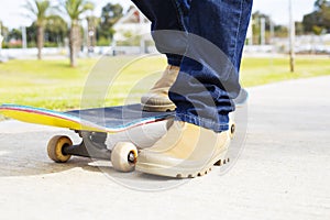 Young skateboarder legs riding skateboard at skatepark.