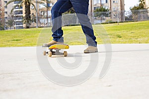 Young skateboarder legs riding skateboard at skatepark.