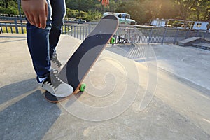 Young skateboarder legs riding skateboard at skatepark