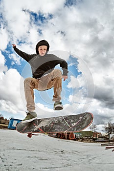 A young skateboarder makes Wallie in a skatepark, jumping on a skateboard into the air with a coup