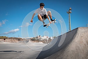 Young skateboarder man does a trick called `boneless` in a ramp of a skate park.