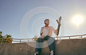 Young skateboarder sitting with his board on the ramp of a skate park. Active lifestyle concept