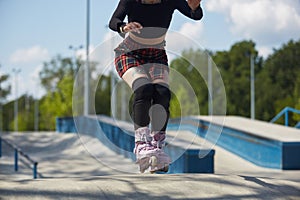 Young skater girl riding in a skatepark. Aggressive inline roller blader female skating in a outdoor concrete park