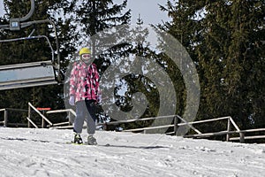 young skier begins to descend from a mid-level ski slope. Active recreation.