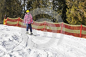 young skier begins to descend from a mid-level ski slope. Active recreation