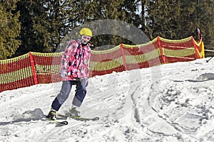 young skier begins to descend from a mid-level ski slope. Active recreation.