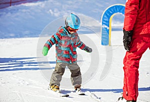 Young skier and ski instructor on slope in beginners` area