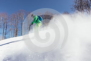 Young Skier skiing downhill during sunny day in high mountains