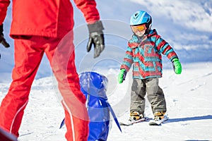 Young skier sliding down towards towards toy penguin and ski ins