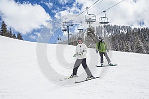 Young skier and a snowboarder skiing and boarding down a ski slope