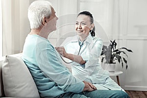 Young skilled nurse sitting and listening to the patients lungs.