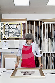 Young skilled worker adjusting frame on photograph