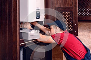 A young skilled worker regulates the gas boiler before use photo
