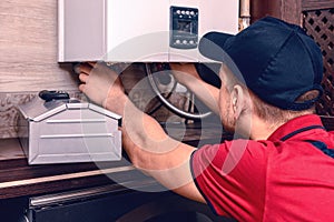 A young skilled worker regulates the gas boiler before use