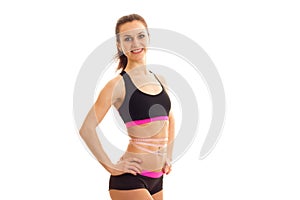 Young skinny girl posing on camera holding hand on the side and smiling on white background