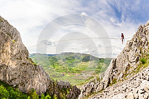 Young slackliner man balancing on a slackline betweend two rocks. Highline with a beautiful natural landscape behind