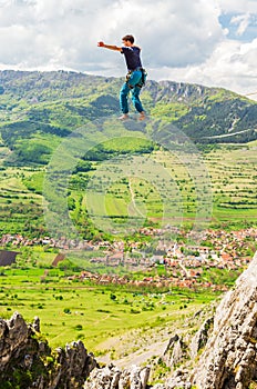 Young slackliner man balancing on a slackline betweend two rocks. Highline with a beautiful natural landscape behind