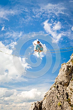 Young slackliner man balancing on a slackline betweend two rocks. Highline with a beautiful natural landscape behind