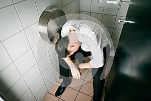 Young sleeping drunk man on the toilette