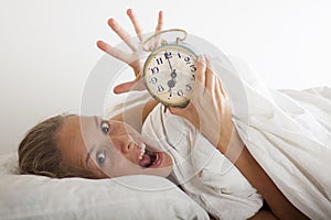 Young sleeping woman and alarm clock in bed