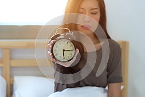 Young sleeping woman and alarm clock in bedroom