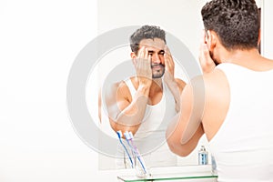 Young sleepy man washing his face