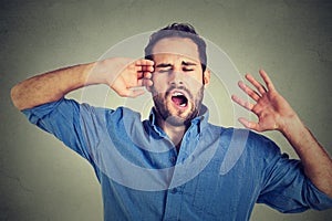 Young sleepy man yawning stretching arms back