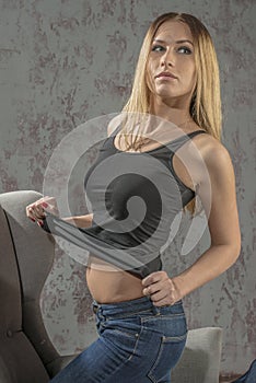 Young slender blonde girl in jeans and shirt posing coquettishly