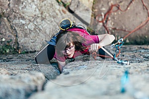 Young slender climber climbs a rock