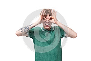 a young slender ginger man with a tattoo on his arm, dressed in a green T-shirt with bright facial expressions