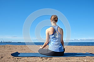 Young slender girl doing yoga on the beach on a sunny morning, sad mood, sad thoughts