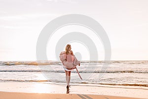 A young slender girl stands alone on the beach or ocean and look at the horizont. A woman dressed in a warm sweater. Toned