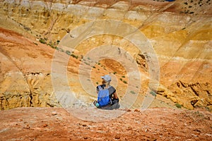 Young slender girl traveler on the background of fantastic Martian landscape in  Altai mountains. Woman in cap with backpack