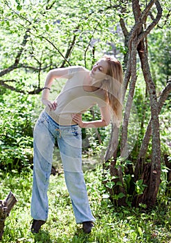 Young slender woman does sporting training in park