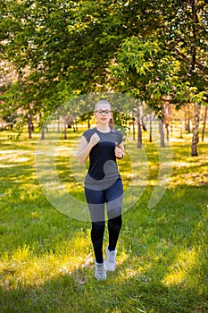 Young, slender woman doing jogging on the spot. Sports activities in the summer park