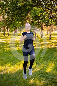 Young, slender woman doing jogging on the spot. Sports activities in the summer park