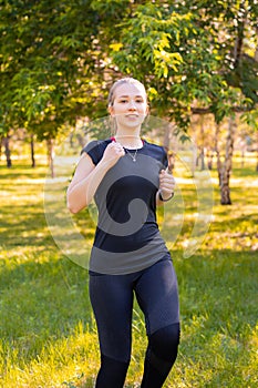 Young, slender woman doing jogging on the spot. Sports activities in the summer park