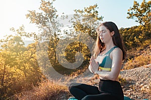 Young slender woman doing yoga and meditating in the Park or forest. The concept of fitness, yoga and sports