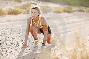 A young slender woman in sportswear is preparing to run from a low start