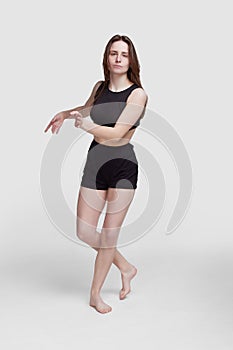 Young slim athletic girl, with long hair, in a black top and shorts, in the studio on a white background