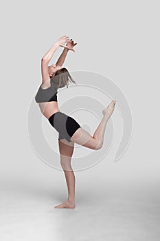 Young slim athletic girl, with long hair, in a black top and shorts, in the studio on a white background