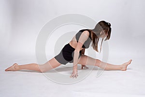 Young slim athletic girl, with long hair, in a black top and shorts, in the studio on a white background