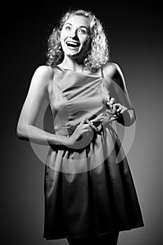 Young slim beautiful blond woman model with curly hair in dress standing and smiling over white background