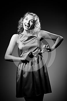 Young slim beautiful blond woman model with curly hair in dress standing and smiling over white background