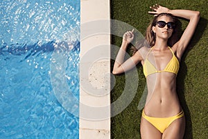 Young slim beautiful woman in yellow bikini sunbathing