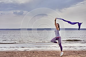 Young slim brunette woman jumping while jogging while holding a blue scarf in her hands. A woman is engaged in gymnastics in the s