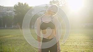 Young slim Caucasian woman warming up at sunrise outdoors. Portrait of confident beautiful brunette sportswoman