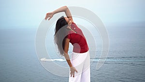 Young slim female doing yoga pose near the sea