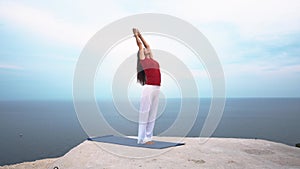 Young slim female doing yoga pose near the sea